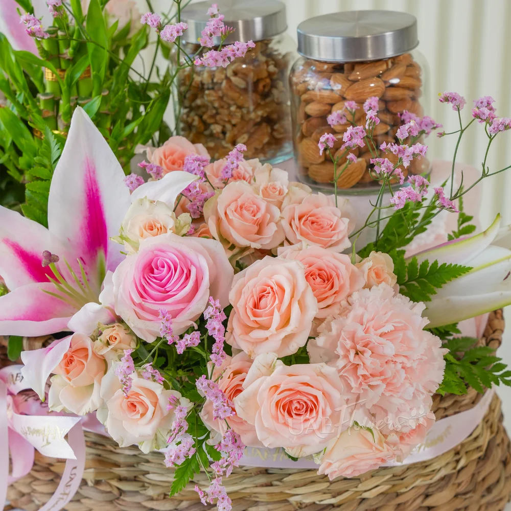 A basket arrangement of 250 Gms of Almonds, 250 Gms of walnut, 3 layer lucky bamboo, 2 pink lilies, 3 pink carnations, 5 pink roses and 4 pink spray roses with limonium fillers.