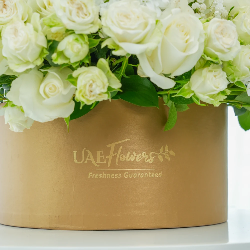 A box arrangement of 20 white orchids, 20 white roses, 5 white spray roses with white chrysanthemums and steel grass.