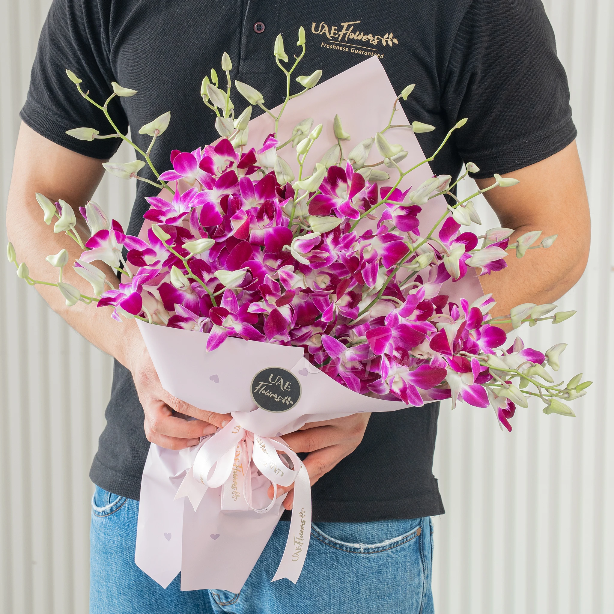 Bouquet of 20 purple orchids with fillers in a pink wrapping paper.