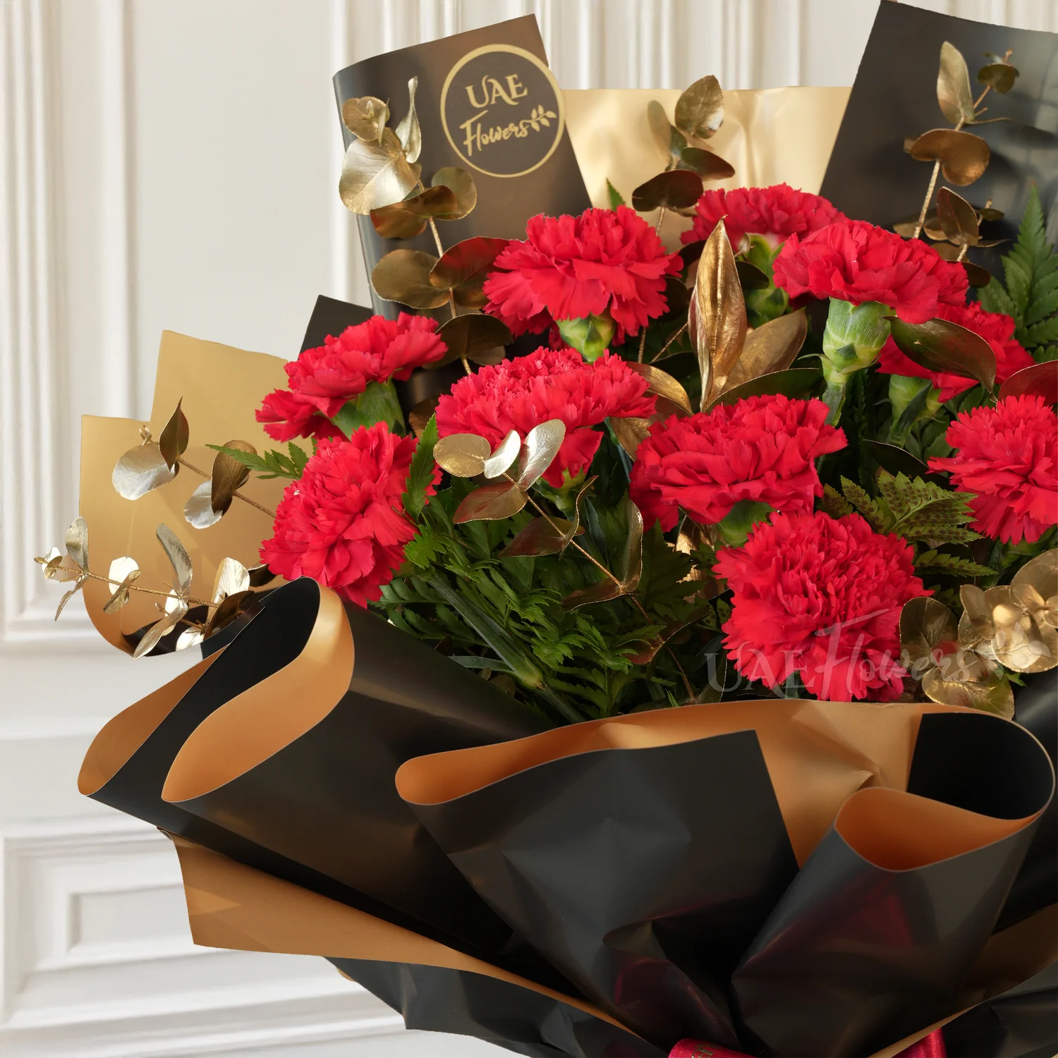 bouquet of 10 red carnations with golden eucalyptus in black and gold wrap