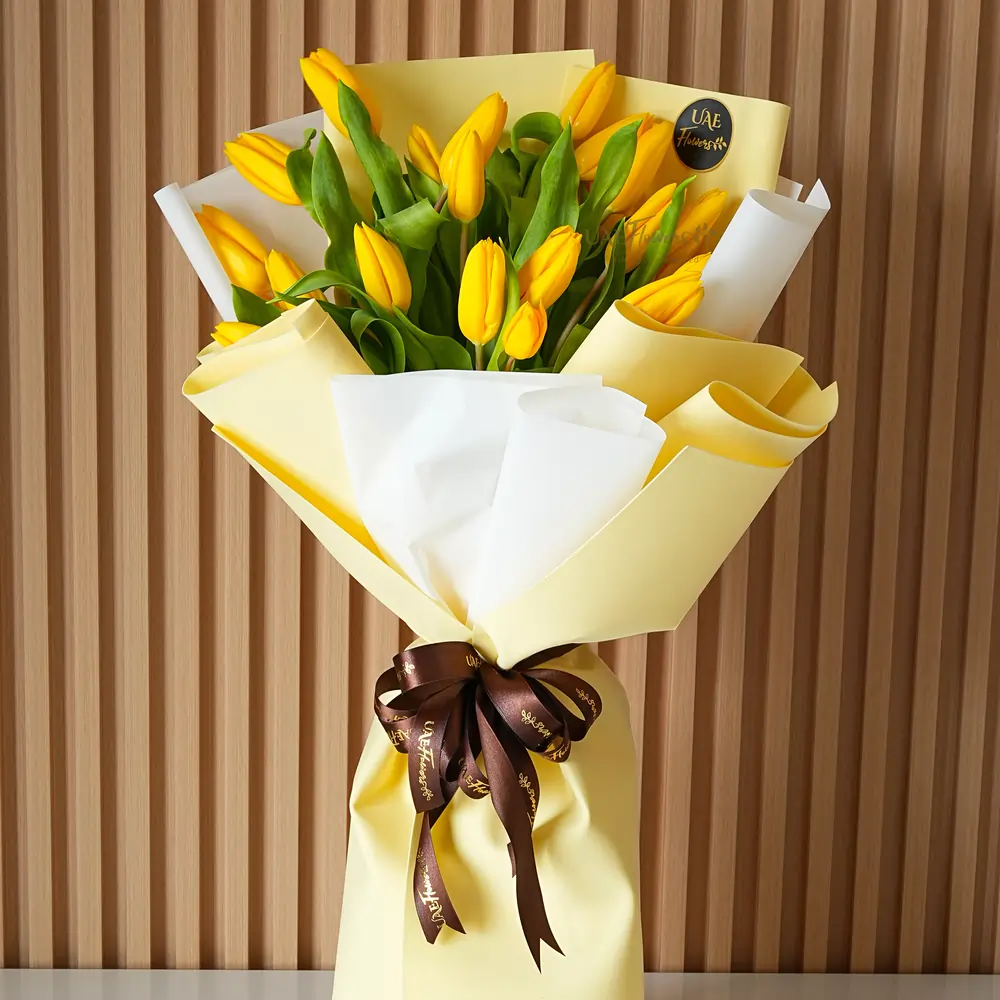 yellow tulips wrapped in yellow and white paper with a ribbon