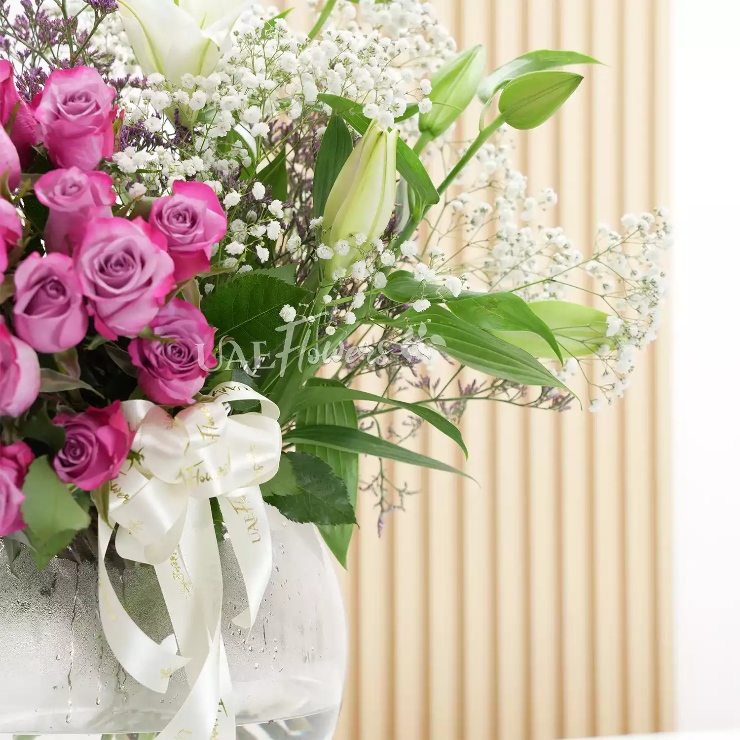 50 purple roses and 2 white lilies in a vase