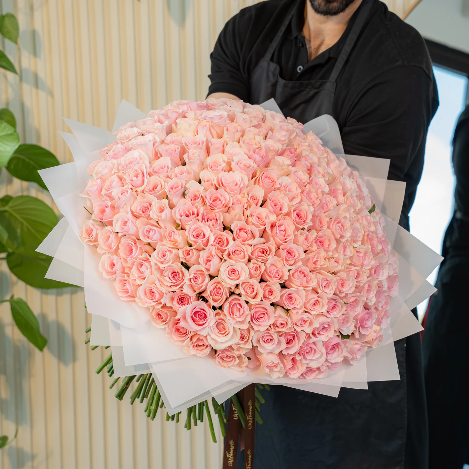 Luxurious bouquet of 200 handtied pink roses wrapped in white paper and tied with satin ribbon – elegant grand floral gift by UAE Flowers.
