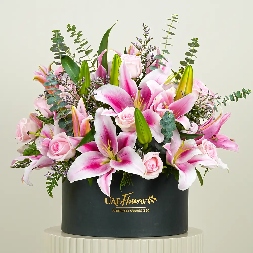 5 pink lilies and 12 pink roses with eucalyptus leaf and limonium fillers in a black round box