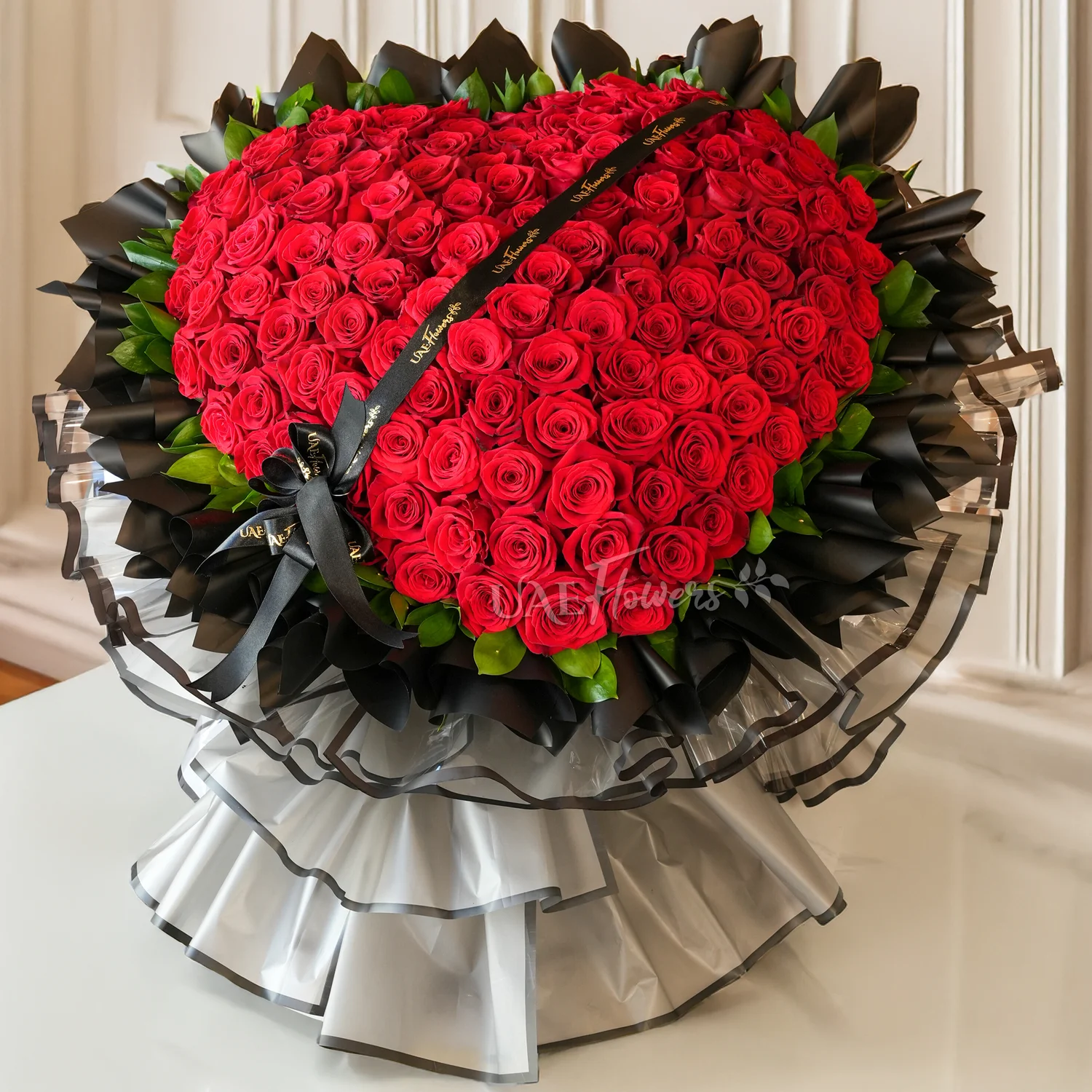 heart-shaped bouquet of 150 red roses wrapped in black and grey paper tied with ribbons