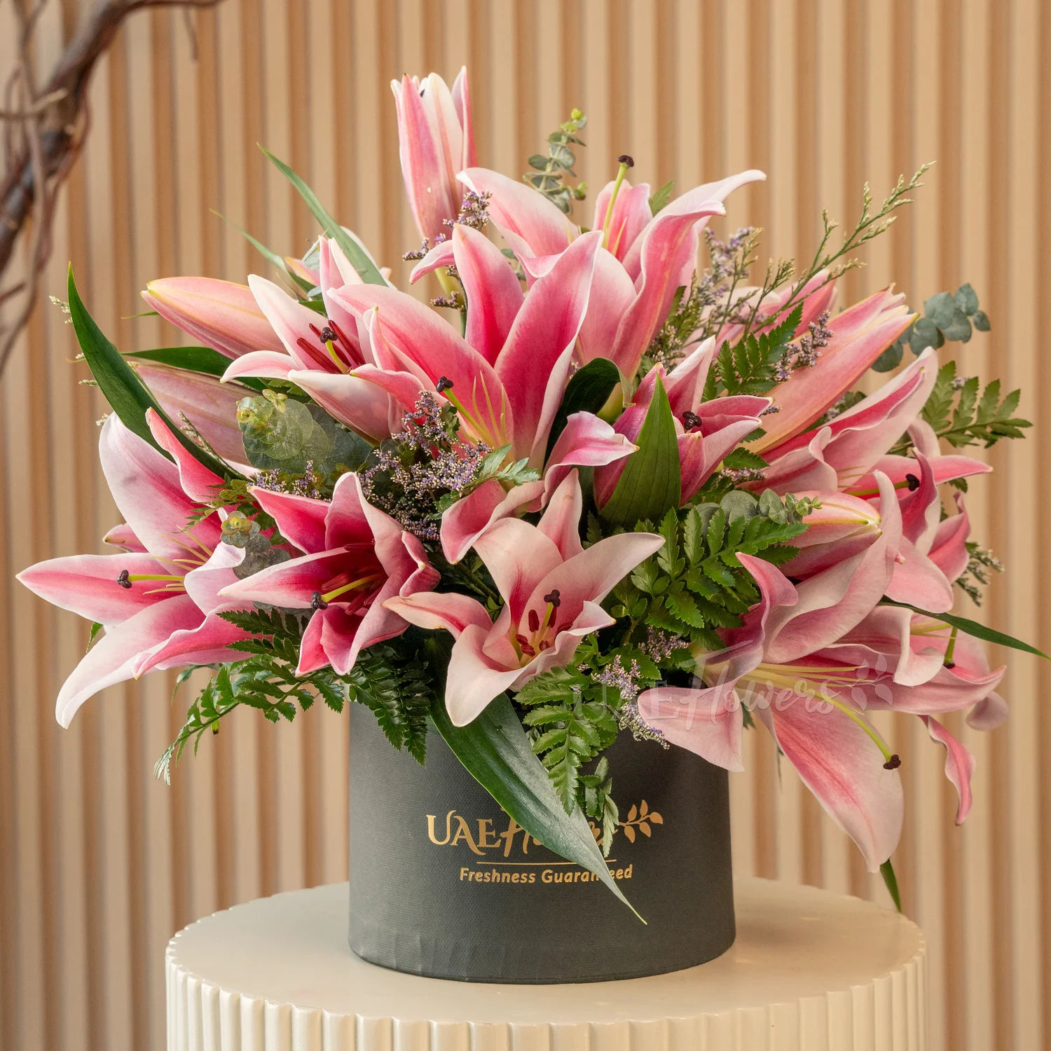 5 pink lilies with eucalyptus leaf and limonium fillers in a black round box